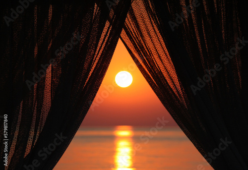 View on sunrise at sea behind curtain, morning light, new day