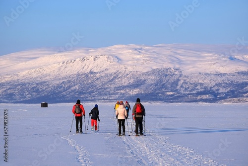Silhouettes of tourists on snowshoes on lake Torneträsk (Tornestrask) around Abisko National Park (Abisko nationalpark) in winter scenery. Sweden, Arctic Circle, Swedish Lapland