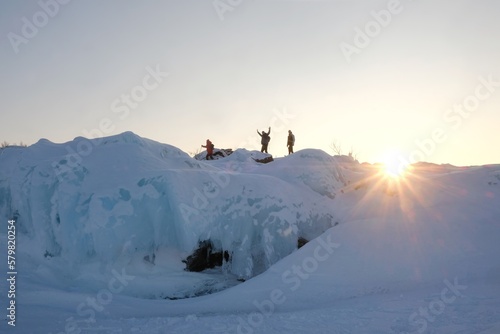 Silhouettes of tourists on snowshoes on island on lake Torneträsk (Tornestrask) around Abisko National Park (Abisko nationalpark) in sunset winter scenery. Sweden, Arctic Circle, Swedish Lapland