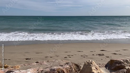 Olas rompiendo en la playa, con rocas en primer término