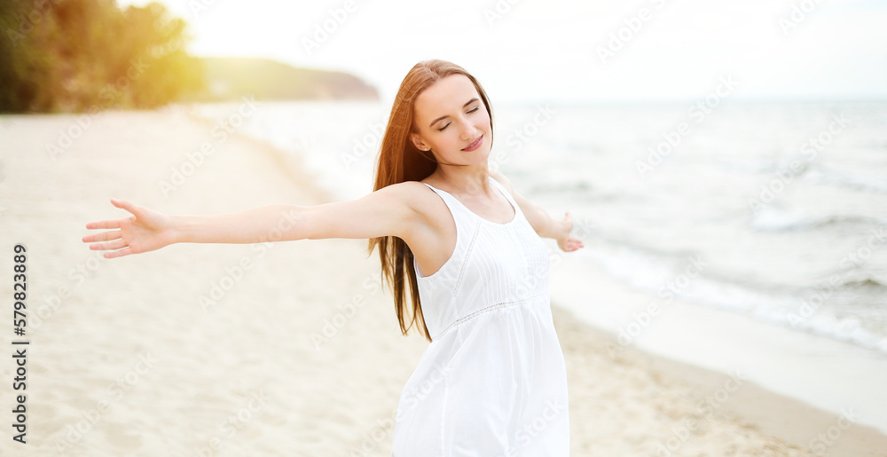 Happy smiling woman in free happiness bliss on ocean beach standing with open hands. Portrait of a multicultural female model in white summer dress enjoying nature during travel holidays vacation Happy smiling woman in free happiness bliss on ocean beach standing with open hands. Portrait of a multicultural female model in white summer dress enjoying nature during travel holidays vacation