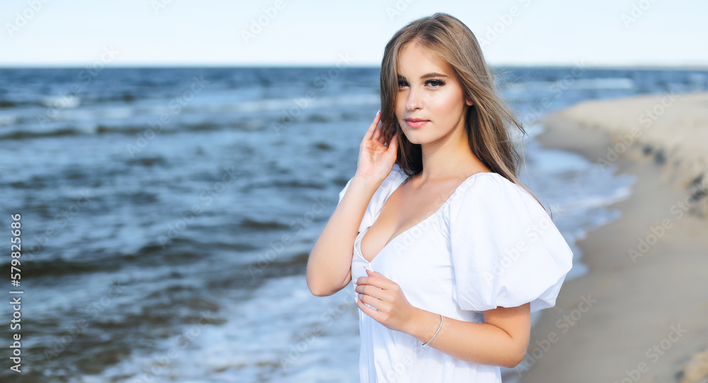 Happy, beautiful woman on the ocean beach standing in a white summer dress. Portrait. Happy, beautiful woman on the ocean beach standing in a white summer dress. Portrait.