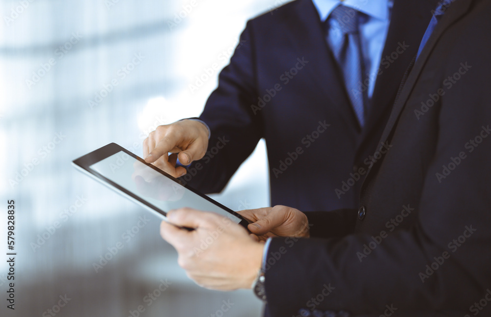 Business people using a tablet computer, while working together in a modern office. Unknown businessman or male entrepreneur with a colleague at workplace. Teamwork and partnership concept Business people using a tablet computer, while working together in a modern office. Unknown businessman or male entrepreneur with a colleague at workplace. Teamwork and partnership concept