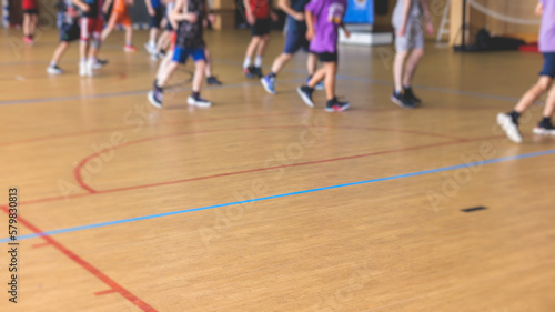 Junior teenage school team of kids children play basketball, players in the hall indoor venue court, sports team during the game, playing indoor match game on arena stadium on a wooden parquet floor © tsuguliev