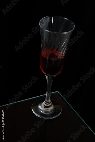 glass goblet with red drink isolated on black background