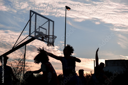 street basketball game with silhouettes of players competing for the ball photo