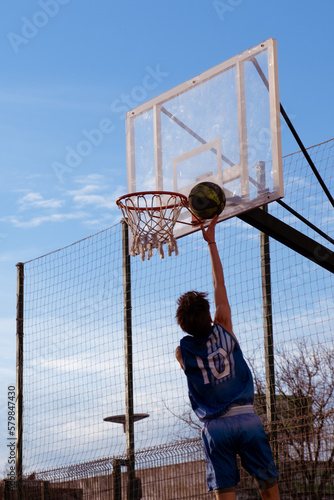 young boy jumping up playing basketball to basket the ball © Noelia Urbano