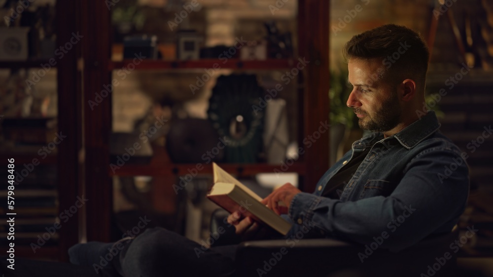 Man sitting in dark room at home reading book, relaxing. Man sitting in dark room at home reading book, relaxing.