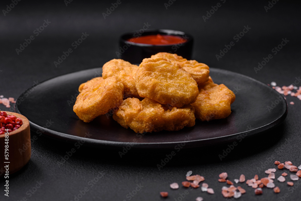 Delicious crispy chicken nuggets with salt and spices on a dark concrete background Delicious crispy chicken nuggets with salt and spices on a dark concrete background