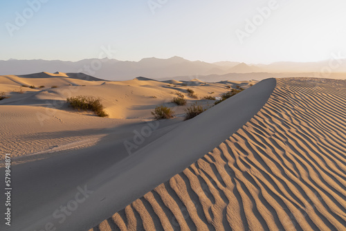 Fototapeta Naklejka Na Ścianę i Meble -  Scenic view on natural ripple sand pattern during sunrise at Mesquite Flat Sand Dunes, Death Valley National Park, California, USA. Morning walk in Mojave desert with Amargosa Mountain Range in back