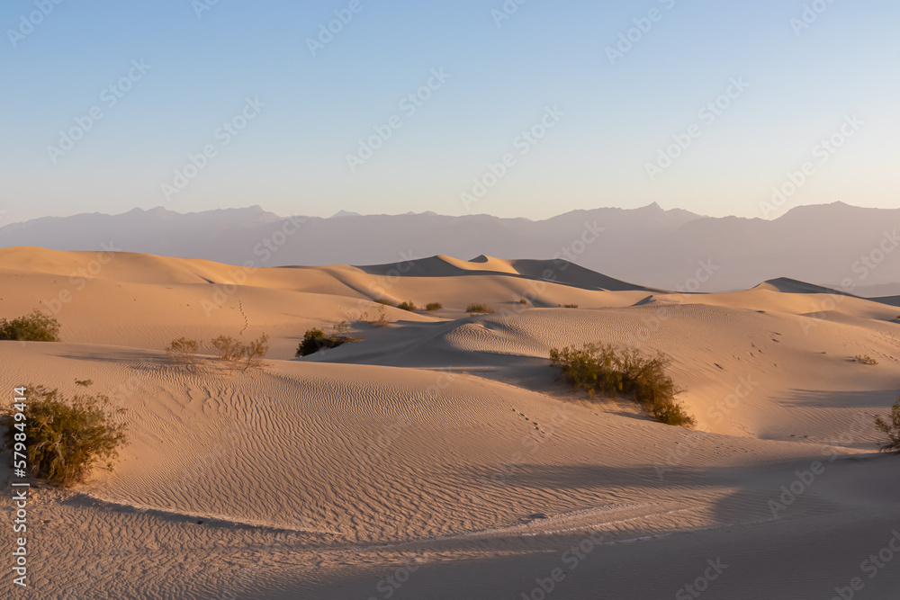 Scenic view on natural ripple sand pattern during sunrise at Mesquite Flat Sand Dunes, Death Valley National Park, California, USA. Morning walk in Mojave desert with Amargosa Mountain Range in back