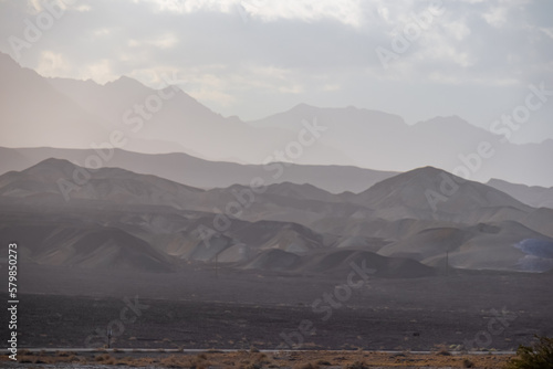 Panoramic sunrise view of the silhouette of Amargosa Mountain and Panamint Mountain Range in Death Valley National Park, California, USA. Hot air and morning atmosphere in the Mojave desert. Sunbeams