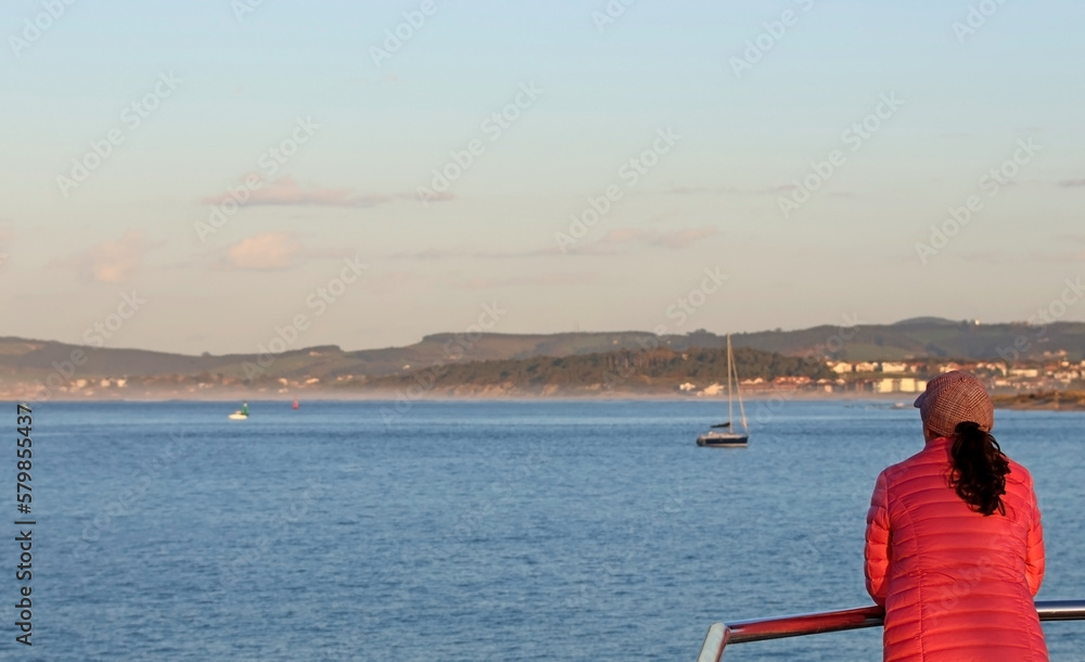 Fototapeta premium Woman in pink jacket looking at the horizon in a coastal landscape.