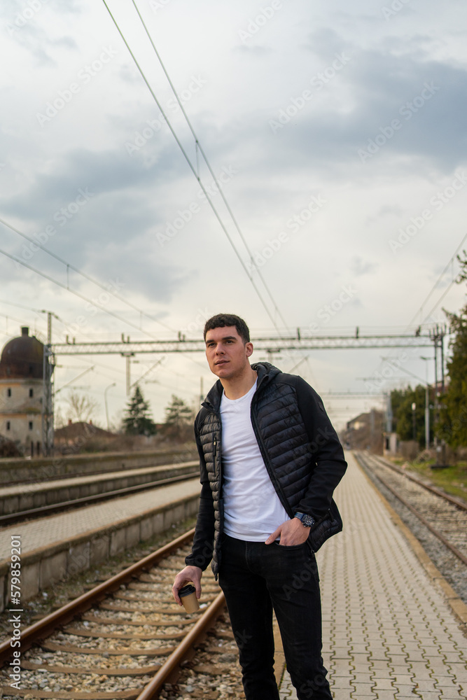 Young man standing on train station and looking for a train. Young man standing on train station and looking for a train.