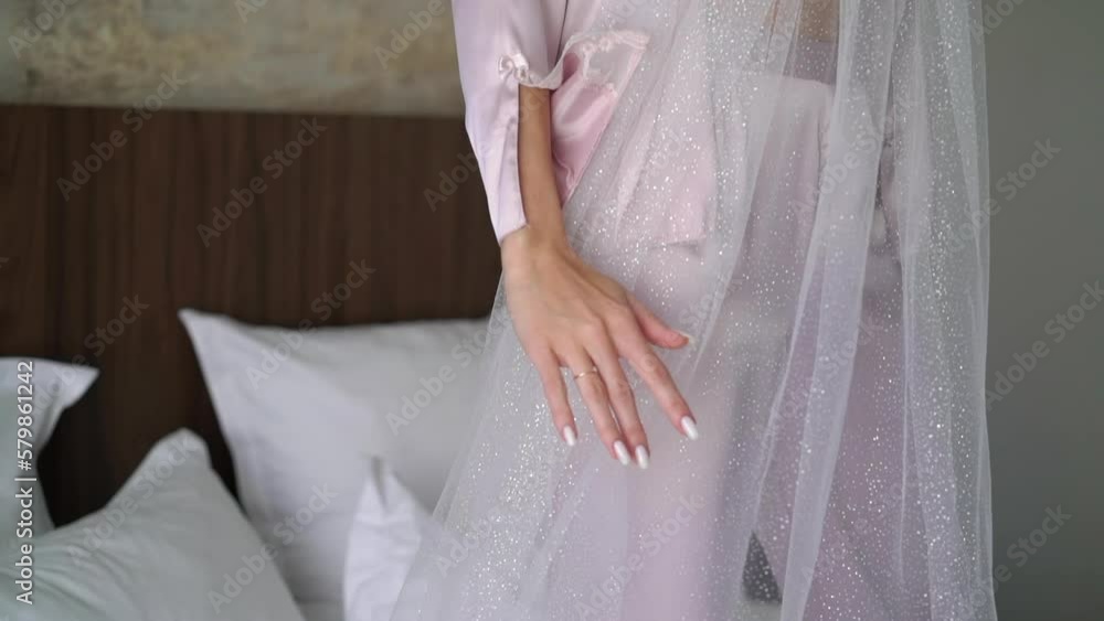 The bride in the morning in robe under her veil, spinning. Woman in underwear - white bra and pink robe in bedroom. The bride in the morning in robe under her veil, spinning. Woman in underwear - white bra and pink robe in bedroom.
