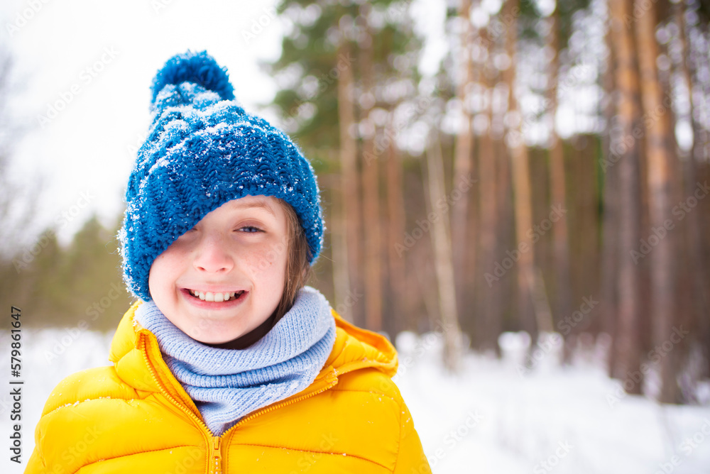 portrait of a happy emotional boy in a hat on his side, the hat covers one eye, the child laughs and rejoices. winter in the snowy forest. portrait of a happy emotional boy in a hat on his side, the hat covers one eye, the child laughs and rejoices. winter in the snowy forest.