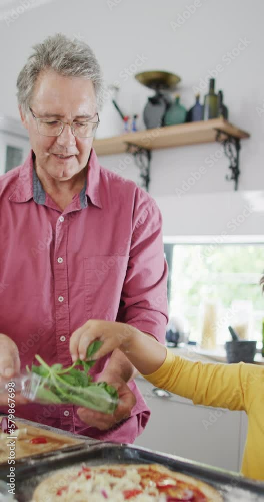 Vertical video of happy caucasian father and son making pizza in kitchen, slow motion Vertical video of happy caucasian father and son making pizza in kitchen, slow motion