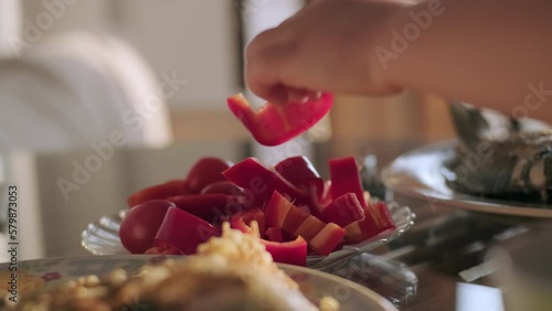 Wallpaper Mural child hand takes red pepper from plate at lunch or dinner. set table with vegetables and fried fish. Torontodigital.ca