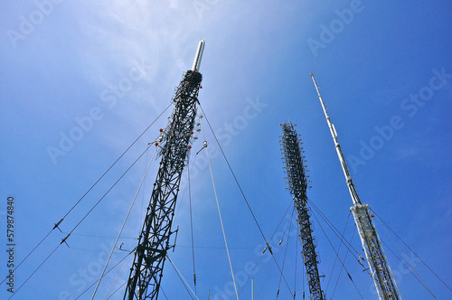 Low-angle view of repeater towers against clear blue sky