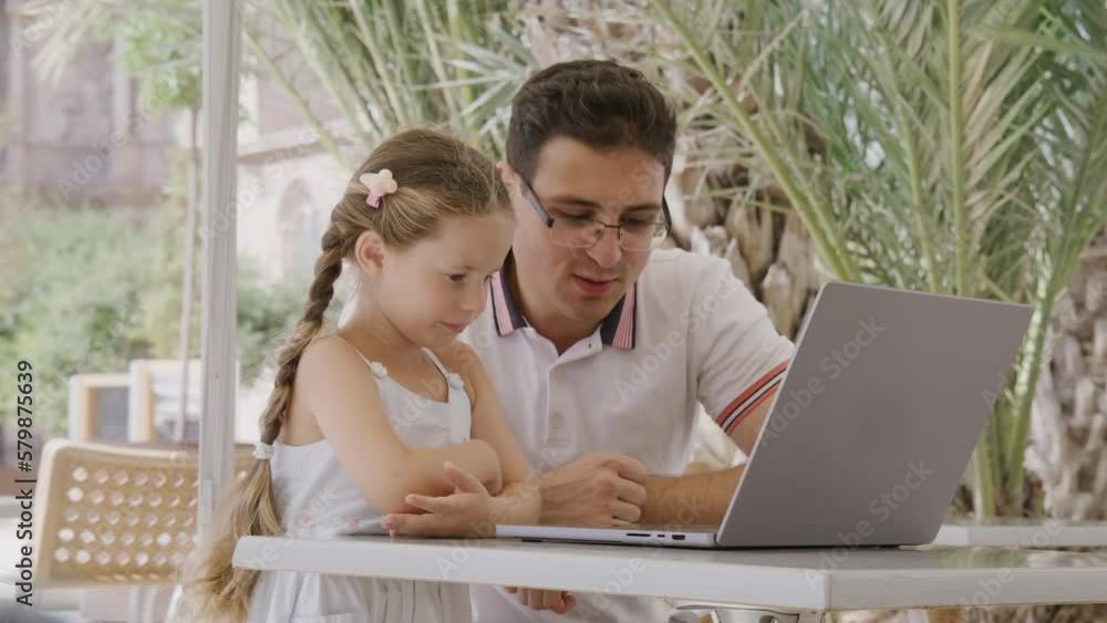 Portrait of a teenager in glasses teaching his cute sister to type on a keyboard. Close-up view of a brother studying remotely while his sibling standing by. High quality 4k footage Portrait of a teenager in glasses teaching his cute sister to type on a keyboard. Close-up view of a brother studying remotely while his sibling standing by. High quality 4k footage