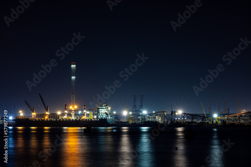 shipyard dry dock maintenance and repair container ship transport and oil ship tanker, crane work and commercial port reflection in water, business and industry zone at night 