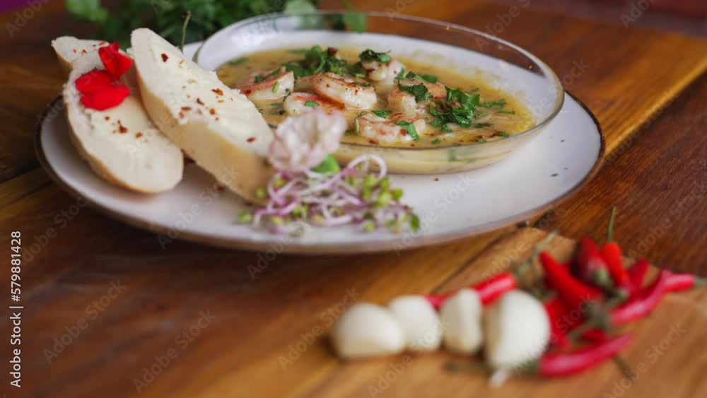 Shrimp in hot sauce topped with parsley served with garlic bread and fresh salad placed next to fresh garlic and red chillies on a wooden table. High quality 4k footage Shrimp in hot sauce topped with parsley served with garlic bread and fresh salad placed next to fresh garlic and red chillies on a wooden table. High quality 4k footage