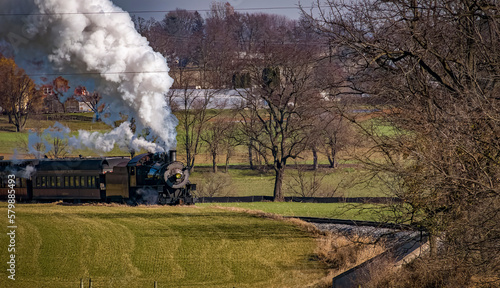 A View of An Antique Passenger Train Approaching, Blowing Smoke and Steam, on an Autumn Day