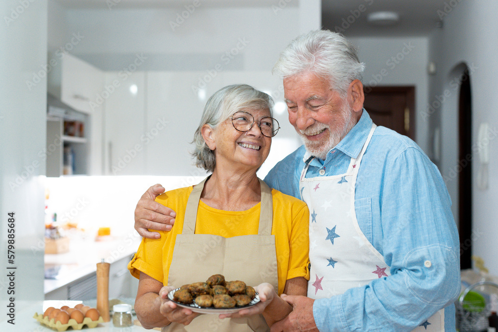 Headshot portrait of cute old couple of seniors showing to camera what they cooked. Together people at home cooking in the kitchen. Healthy food concept diet holding meatballs. Headshot portrait of cute old couple of seniors showing to camera what they cooked. Together people at home cooking in the kitchen. Healthy food concept diet holding meatballs.