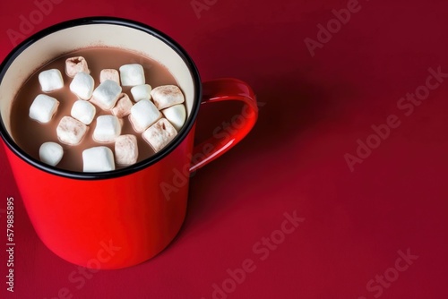 red mug with hot chocolate with small marshmallows on red background