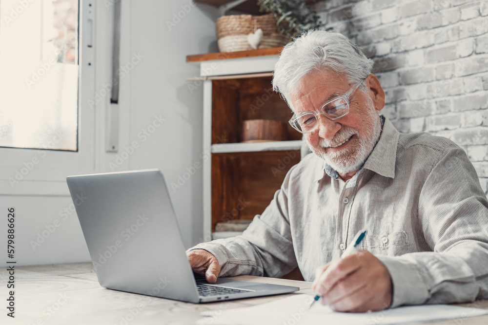Aged remote worker. Concentrated senior male in glasses work on laptop from home office read email electronic document. Old age man employee freelancer sit at kitchen table by pc typing report online. Aged remote worker. Concentrated senior male in glasses work on laptop from home office read email electronic document. Old age man employee freelancer sit at kitchen table by pc typing report online.