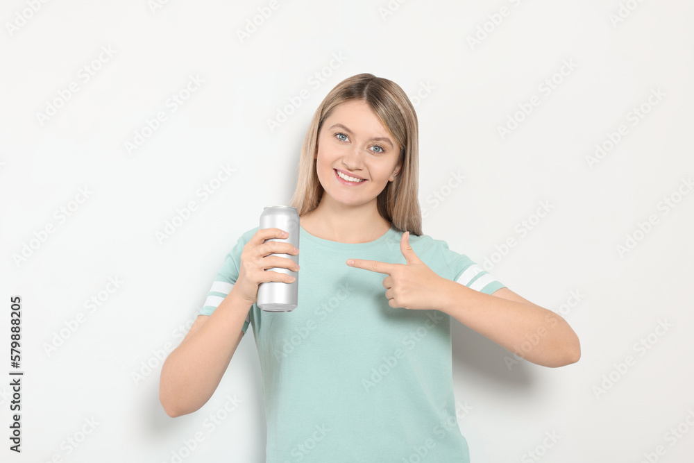 Beautiful happy woman holding beverage can on light background Beautiful happy woman holding beverage can on light background
