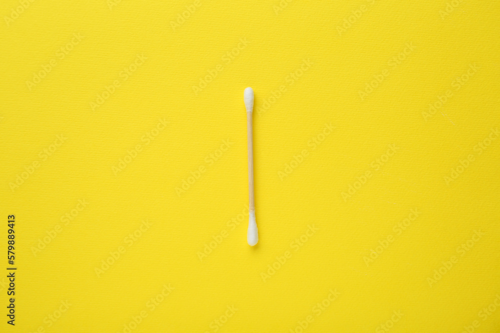 One wooden cotton bud on yellow background, top view One wooden cotton bud on yellow background, top view