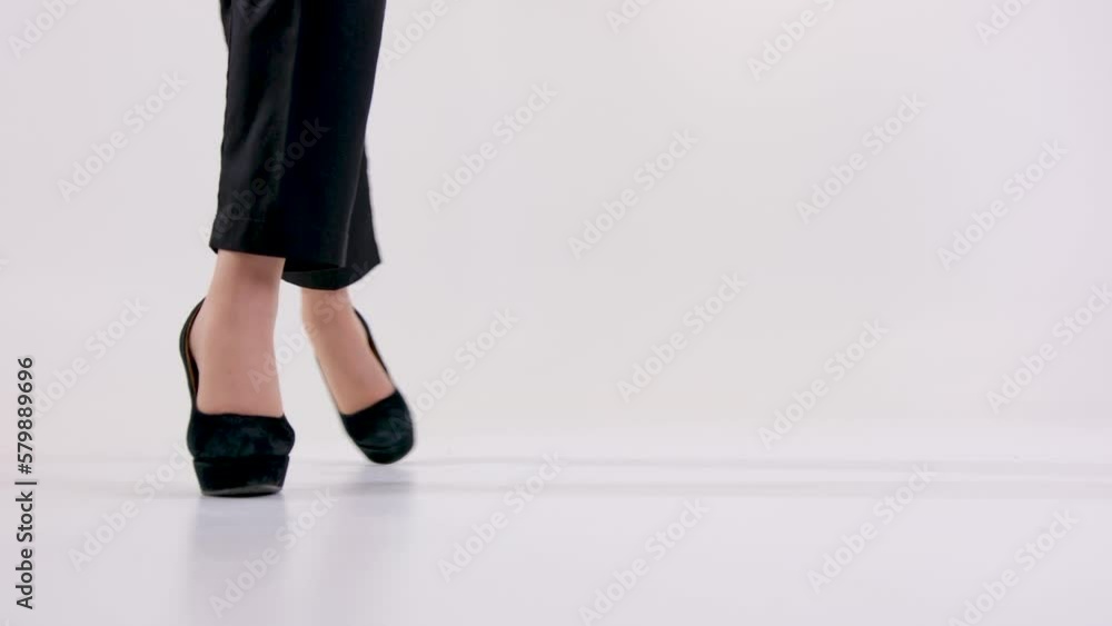 female legs in high heeled shoes in white studio casually walking freely woman calmly life satisfaction businesswoman boss space for text unrecognizable people black trousers high soles female legs in high heeled shoes in white studio casually walking freely woman calmly life satisfaction businesswoman boss space for text unrecognizable people black trousers high soles