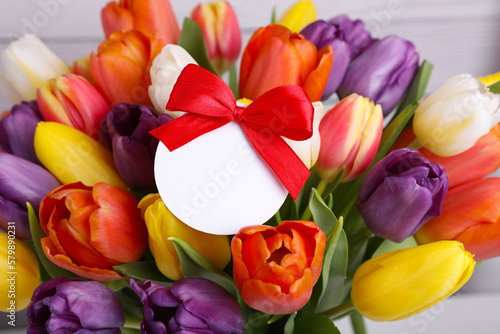 Bouquet of beautiful colorful tulips with blank card on white wooden background  closeup. Birthday celebration