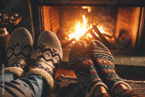 Fotografia Young romantic couple sitting on sofa in front of fireplace, Warming and relaxing near fireplace
