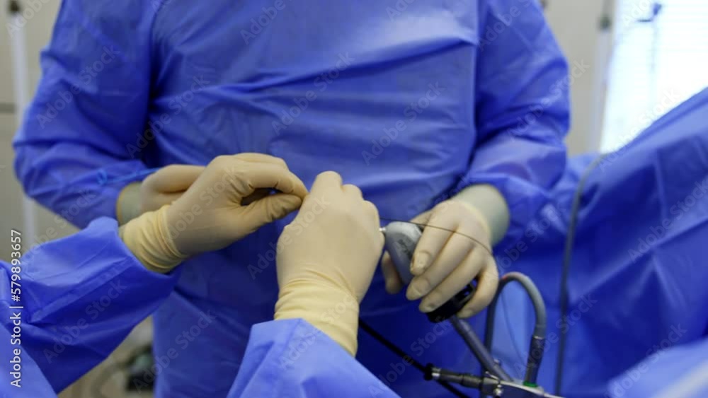 Preparing the tools for usage at surgery. Close up. Nurse is helping the surgeon. Doctor is holding a device.