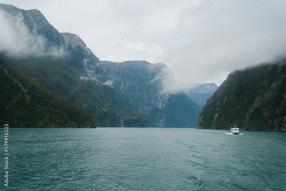 Fototapeta premium Small boat next to huge mountains, Milford Sound