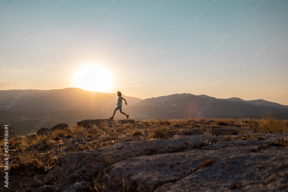 silhouette of a running man against the background of the sky and sunset in the mountains, sports and recreation. - obrazy, fototapety, plakaty 