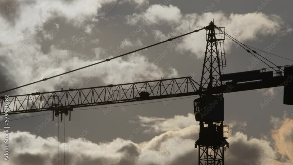 Timelapse, silhouette of tower crane working at construction site. High-rise crane with jib rotates on background of sunset sky with clouds. Timelapse, silhouette of tower crane working at construction site. High-rise crane with jib rotates on background of sunset sky with clouds.