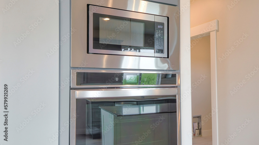 Panorama Built-in double oven and microwave on a wall with gray cabinet doors on top Panorama Built-in double oven and microwave on a wall with gray cabinet doors on top
