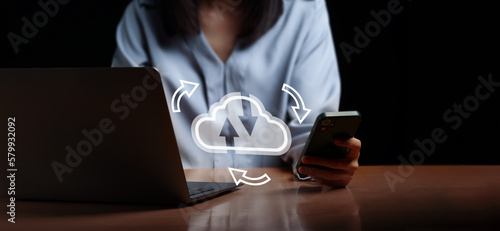 A women is syncing data between smartphone and laptop then upload data on cloud service. The image show concept of using cloud technology and eco system by modern device.
