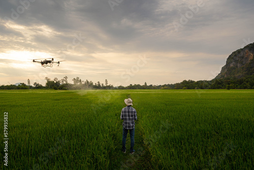Agricultural specialist controls agriculture drone with remote controller for spraying fertilizer and pesticide at rice field. Agriculture 5g, Smart farming, Smart technology concept..