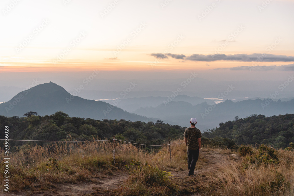 The man stand alone at top of mountain and sightseeing beautiful hill and sunrise, grain and noise for tone picture