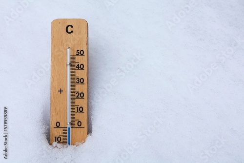 Wooden thermometer in the snow. Freezing temperature. Copy space.