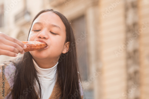 Close up young brunette teenager enjoying eating churros