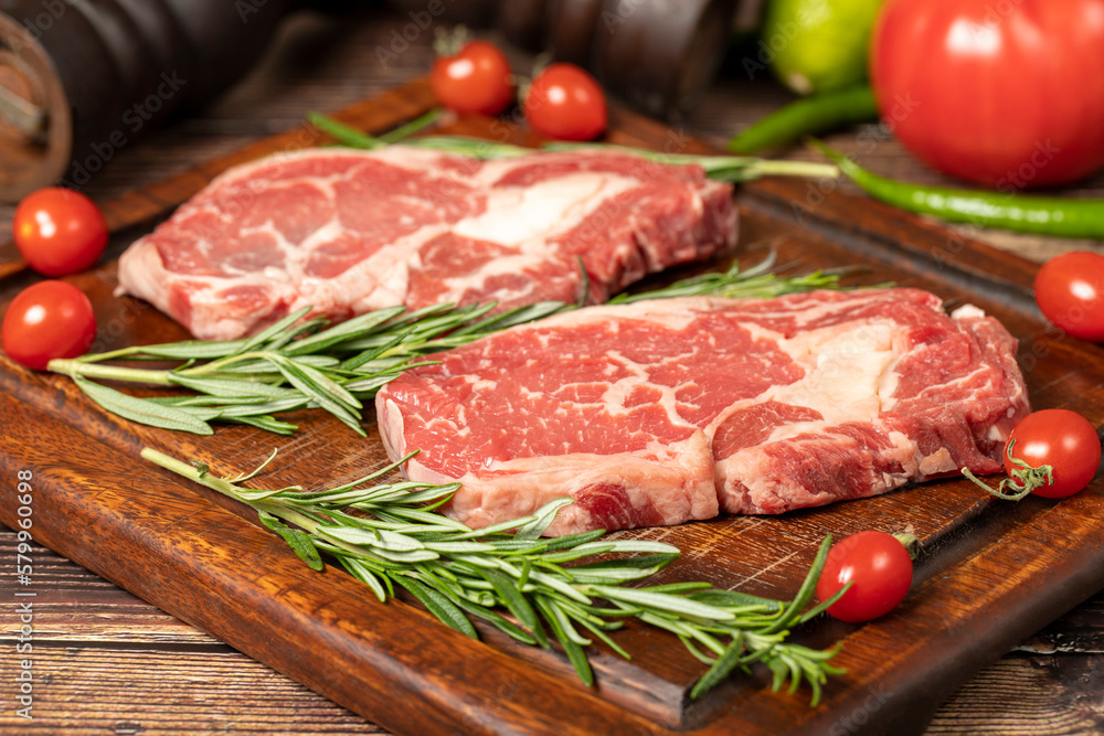 Beef ribeye. Two fresh raw ribeye steaks with spices and rosemary. Special entrecote. wood background. Close up