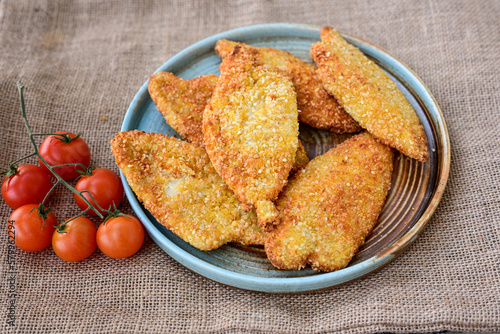 
 Crispy oven baked  chicken breast with sesame seeds and ketchup. Breaded chicken fillets  with chilly peppers and fresh basi on wooden rustic background