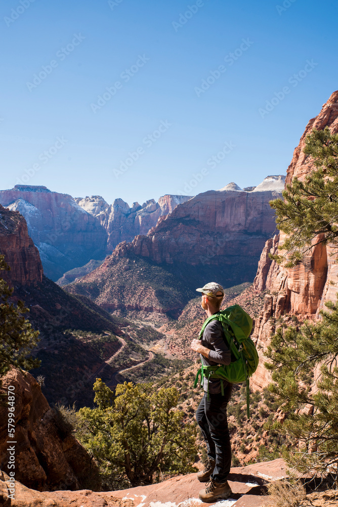 Full length of hiker with backpack looking at rock formations while standing on desert against clear sky Full length of hiker with backpack looking at rock formations while standing on desert against clear sky