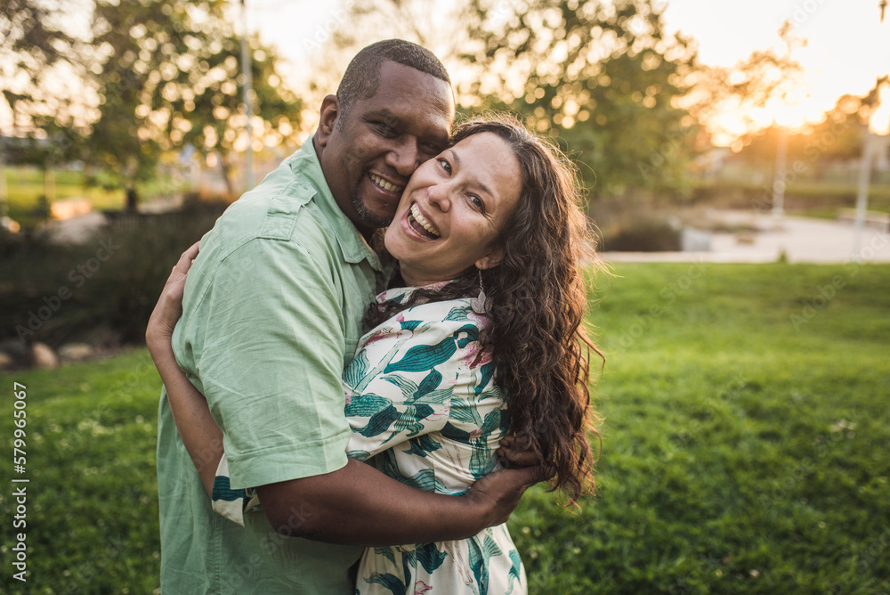Portrait of cheerful couple embracing on field at park Portrait of cheerful couple embracing on field at park