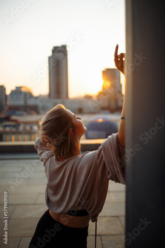 Photo shoot on the roof. Young woman posing in the roof at sunset. Fashion, style concept. © maxbelchenko